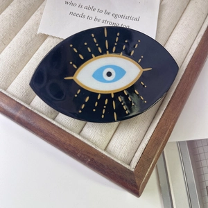 Detail shot of a black Evil Eye hair claw clip featuring blue eye and golden details