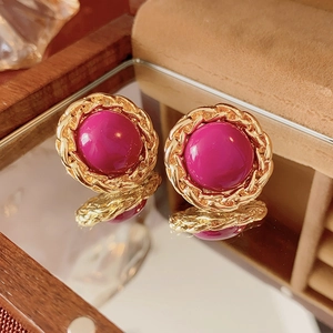 Detail of vintage round earrings with purple center and golden braided chain border