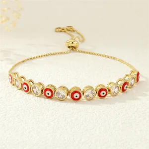 Detail of gold adjustable bolo bracelet with red enamel evil eyes and white zircon stones