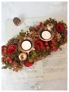 Close-up of vintage Christmas candle holder with red berries, gold pinecones and white candles