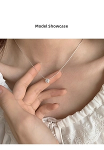 Macro detail of a minimalist zircon pendant necklace on a model showing the claw setting