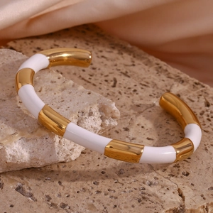 Detailed macro view of 18K gold plated bangle with white enamel segments on silk