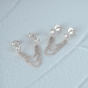 Macro detail of S925 sterling silver evil eye stud earrings with cascading chain tassels