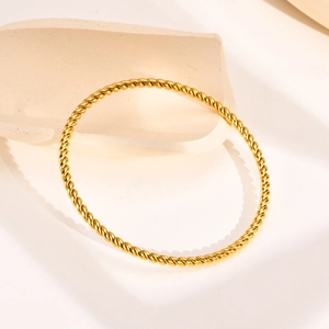 Detailed macro view of the golden twisted rope pattern on the stainless steel bangle