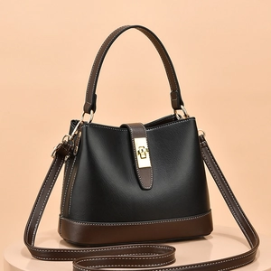 Chic black and brown leather bucket bag with gold buckle on a neutral pedestal