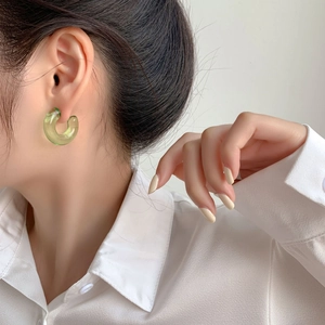 Elegant green transparent resin C-shape hoop earrings worn by a fashion model
