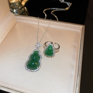 Close-up of resin gourd pendant and ring set with green zircon and silver finish