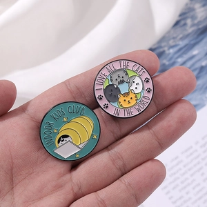 Detail of two round enamel pins featuring cats and Indoor Kids Club text designs