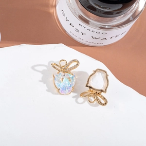 Close-up of golden bow earrings with iridescent crystals on a white display pedestal