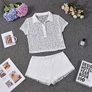 Flat lay of white lace two-piece set with polo crop top and shorts on gray texture