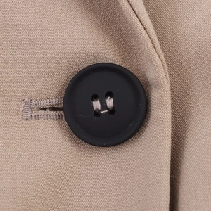 Detailed close-up of a black matte button on khaki textured fabric for women blazer