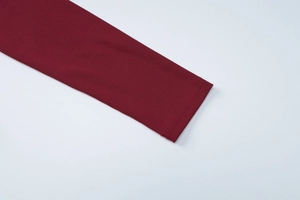 Dettaglio dei polsini in maglia a coste rosso scuro e cuciture fini della maglia a maniche