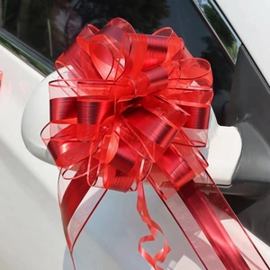 Detail of a large red mesh ribbon bow attached to a white car rearview mirror for weddings