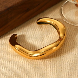 Macro detail of gold irregular wave cuff bracelet with smooth liquid metal texture