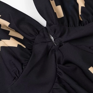 Dettaglio vestito nero con stampa geometrica beige, nodo centrale e texture arricciata