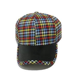 Close-up of multicolor houndstooth pattern fabric and black matte brim on baseball cap