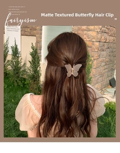 Detailed back view of a frosted butterfly hair claw clip worn on wavy long brown hair