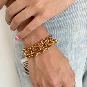 Détail d'un bracelet triple épaisseur en acier inoxydable doré porté sur le poignet