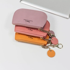 Minimalist textured leather coin purses in pink and coral with golden zipper and tag