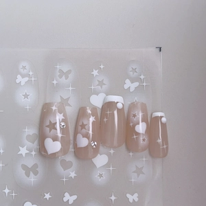 Detail of pink almond nails with white hearts, stars, and rhinestones on clear backing