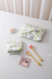 Detail view of two floral jacquard cosmetic bags in purple and light green fabric