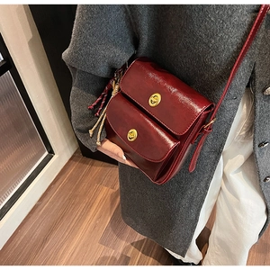 Deep red vintage satchel bag featuring golden metal clasp and woven charm detail