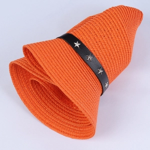 Detail of orange woven straw hat with black leather band and silver star studs