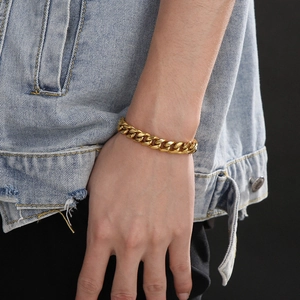 Detail shot of a polished golden stainless steel Cuban chain bracelet on wrist