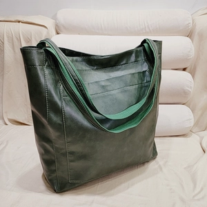 Vue détaillée d'un grand sac cabas vert foncé avec texture cuir et bandoulière tissée