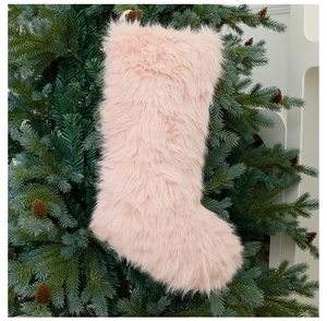 Pink plush Christmas stocking ornament hanging on a festive tree with pine cones