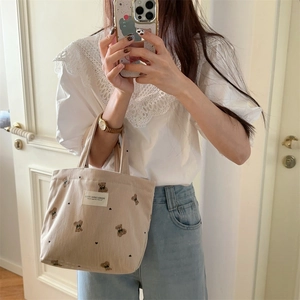 Mirror selfie showing the beige corduroy tote bag with cute bear embroidery details