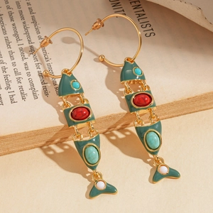 Detailed close-up of dark green fishbone earrings with colorful enamel on a vintage book