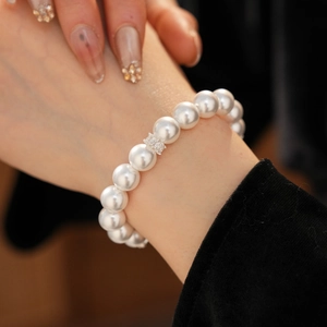 Détail d'un bracelet de perles avec accent en cristal argenté sur le poignet d'un mannequin