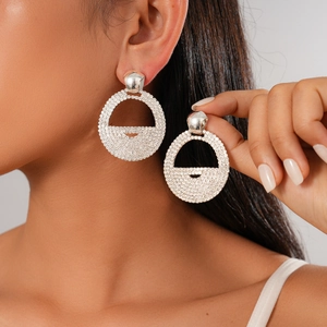 Silver geometric hoop earrings with sparkling rhinestones worn by a model in soft light