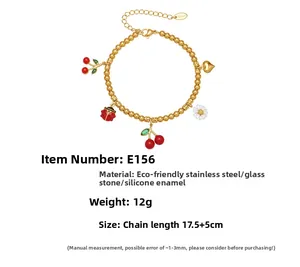 Détail du bracelet à perles dorées avec breloques cerise, marguerite et émail