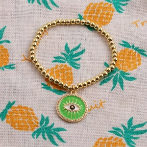 Gros plan d'un bracelet en perles de cuivre doré avec breloque œil porte-bonheur vert