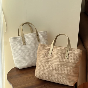 Close-up of woven canvas tote bags with beige wheat pattern and brown faux leather handles