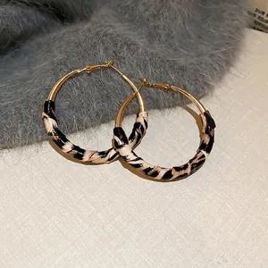 Detailed view of gold hoop earrings with leopard print texture on plush fabric background