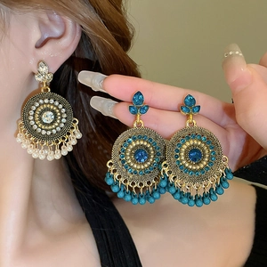 Detail of bohemian drop earrings with blue rhinestones and dangling beads on model