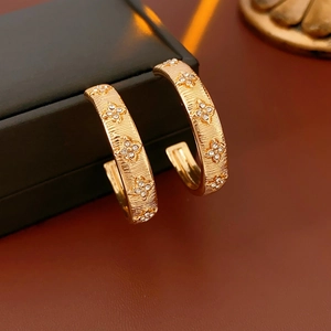 Close-up of golden C-shaped flower earrings with sparkling rhinestones on jewelry box