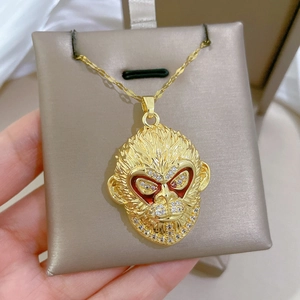 Close-up of gold monkey pendant with red enamel eyes and pavé crystals on a chain