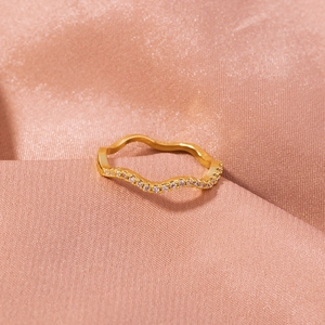 Detailed close-up of a gold-plated wavy ring set with white sparkling zircons