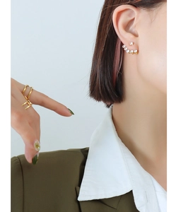 Detail of gold-plated 18k zircon crawler earrings and minimalist rings on female model