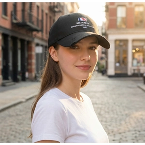 Outdoor portrait of a vintage black baseball cap featuring letter embroidery and distressed brim