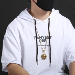 Close-up of a gold sun pendant necklace worn by a model in a casual white hoodie