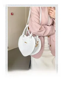 Vue détaillée d'un sac cœur blanc à motif crocodile porté par un mannequin de côté