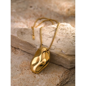 Macro view of 18K gold stainless steel necklace with organic irregular pendant on stones