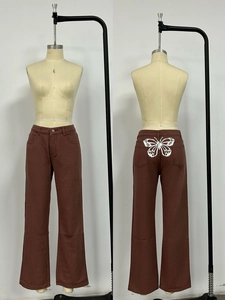 Dettaglio dei pantaloni in denim marrone a gamba larga con stampa a farfalla bianca sul retro