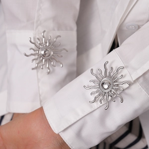 Macro shot of silver sunburst cufflinks on a white shirt sleeve with metallic finish