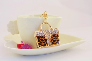 Macro detail of leopard print handbag keychain with crystals and golden metal chain